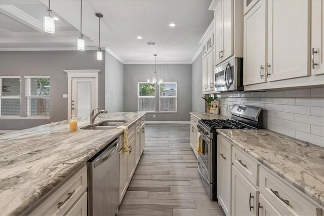 kitchen featuring stainless steel appliances, a sink, wood finished floors, backsplash, and baseboards