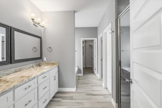 full bathroom with wood finished floors, vanity, a bath, baseboards, and a closet