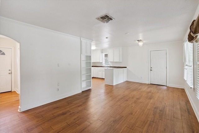 330 Ohio Ave, Corpus Christi, TX 78404 - unfurnished living room featuring arched walkways, wood finished floors, and crown molding