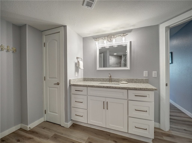 bathroom with a textured ceiling, vanity, and hardwood / wood-style flooring