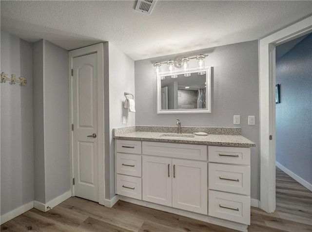 800 Sandcastle Dr Unit 129, Port Aransas, TX 78373 - full bathroom with a textured ceiling, wood finished floors, baseboards, and vanity