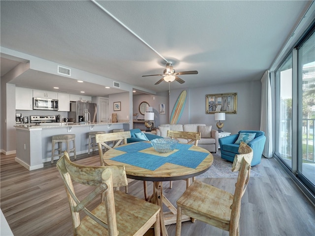 dining area featuring ceiling fan, a textured ceiling, and light wood-type flooring