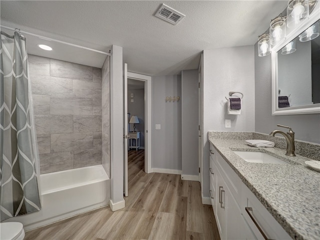 full bathroom featuring shower / bath combination with curtain, a textured ceiling, hardwood / wood-style floors, vanity, and toilet