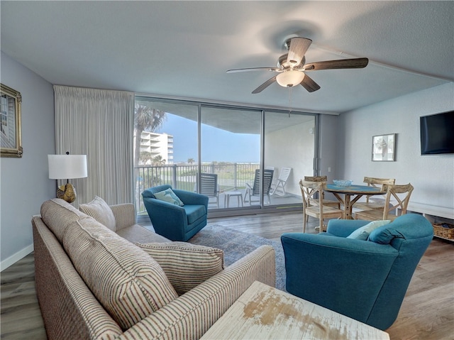 living room featuring expansive windows, wood-type flooring, and ceiling fan