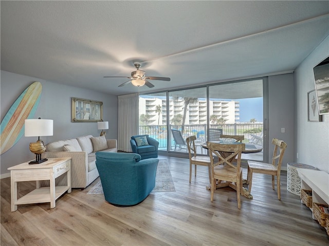 living room with light wood-type flooring, ceiling fan, and a healthy amount of sunlight