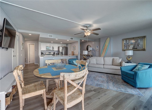 dining space with light hardwood / wood-style floors and ceiling fan