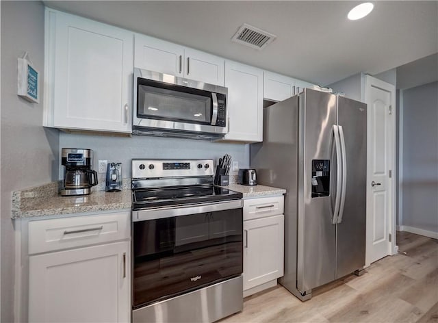 800 Sandcastle Dr Unit 129, Port Aransas, TX 78373 - kitchen with stainless steel appliances, light wood-style flooring, white cabinets, and light stone countertops
