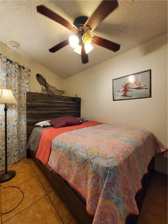 3938 Surfside Blvd Unit 1121, Corpus Christi, TX 78402 - bedroom with tile patterned floors, a textured ceiling, a ceiling fan, and vaulted ceiling