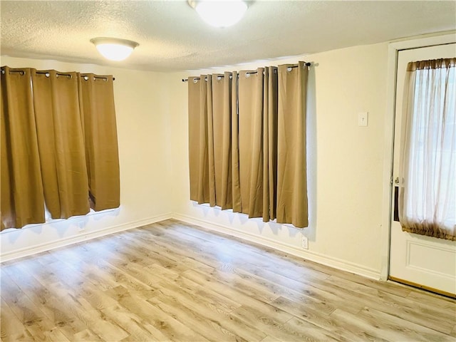 unfurnished room with a textured ceiling and light wood-type flooring