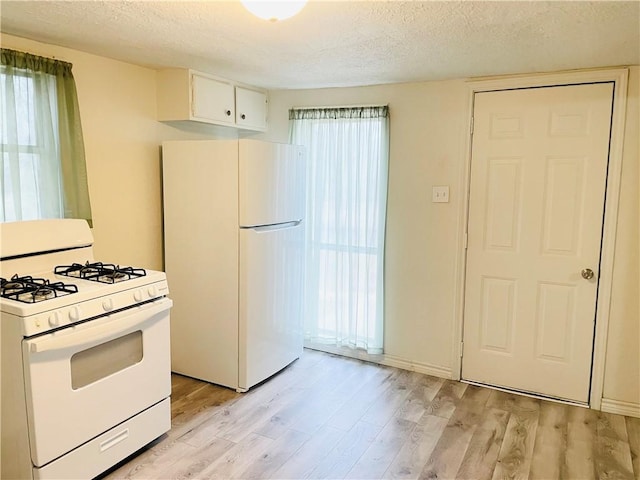 kitchen with light wood-type flooring, white appliances, white cabinetry, and plenty of natural light