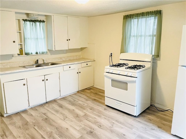 kitchen featuring white cabinetry, sink, white appliances, and light hardwood / wood-style flooring