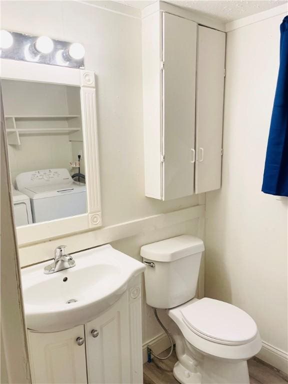 bathroom with washer and clothes dryer, vanity, toilet, and hardwood / wood-style flooring