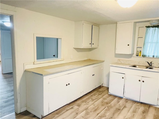 kitchen featuring white cabinets, light wood-type flooring, and sink