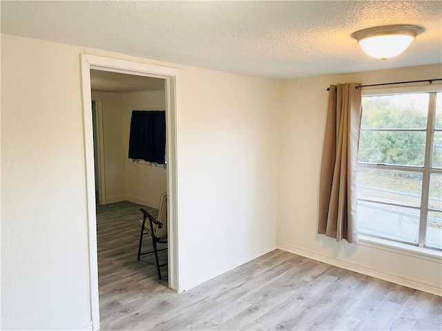 spare room with light hardwood / wood-style floors and a textured ceiling