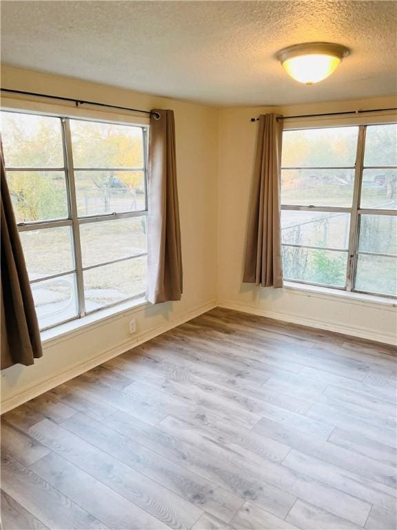 empty room with a textured ceiling and light wood-type flooring