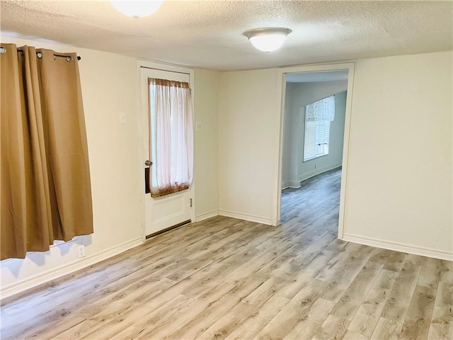 unfurnished room featuring a textured ceiling, light hardwood / wood-style floors, and a healthy amount of sunlight