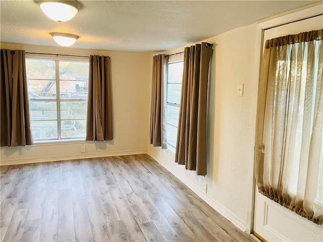 empty room with light hardwood / wood-style floors and a textured ceiling