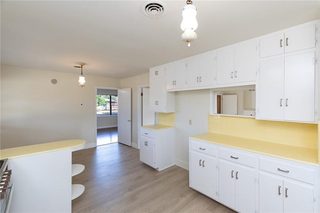 kitchen with white cabinetry, backsplash, decorative light fixtures, light wood-type flooring, and range