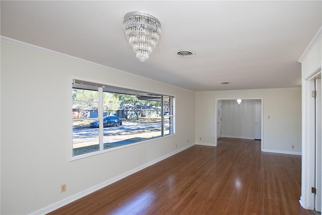 unfurnished room with an inviting chandelier, ornamental molding, and dark hardwood / wood-style floors