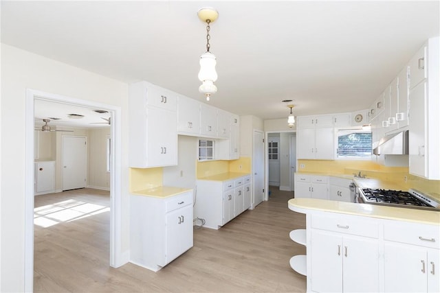 kitchen featuring decorative light fixtures, stainless steel gas stovetop, white cabinetry, and light hardwood / wood-style flooring