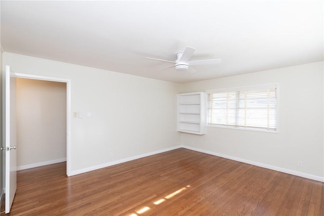 unfurnished room featuring ceiling fan, built in shelves, and wood-type flooring