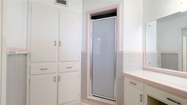 bathroom with tile walls, walk in shower, and vanity