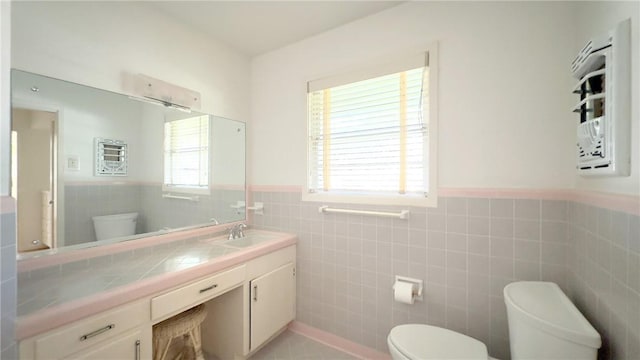 bathroom with toilet, vanity, tile walls, and tile patterned flooring