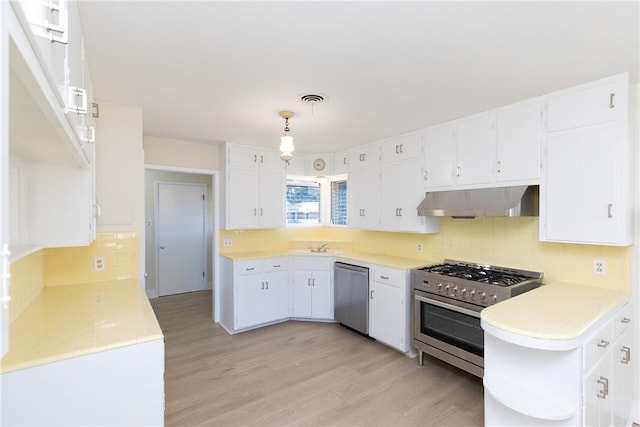 kitchen with white cabinetry, light hardwood / wood-style floors, appliances with stainless steel finishes, decorative backsplash, and decorative light fixtures