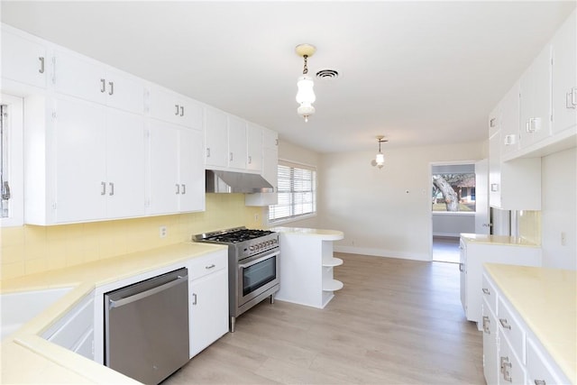 kitchen featuring white cabinets, appliances with stainless steel finishes, decorative light fixtures, tasteful backsplash, and light hardwood / wood-style floors