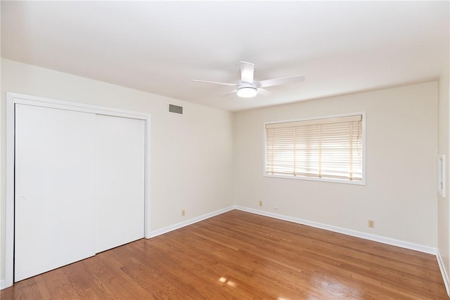 unfurnished bedroom with ceiling fan, a closet, and wood-type flooring