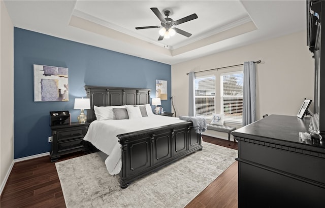 bedroom featuring dark hardwood / wood-style floors, ceiling fan, crown molding, and a tray ceiling