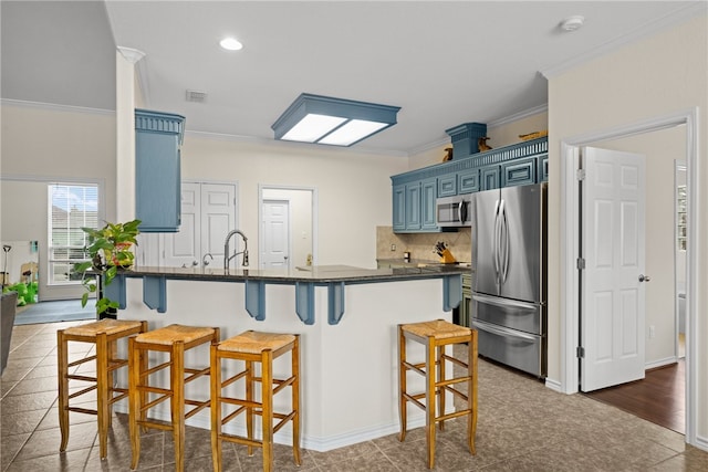 kitchen with blue cabinetry, appliances with stainless steel finishes, a breakfast bar, and ornamental molding