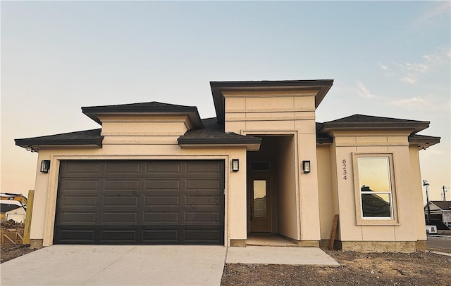 prairie-style home with stucco siding, concrete driveway, and an attached garage