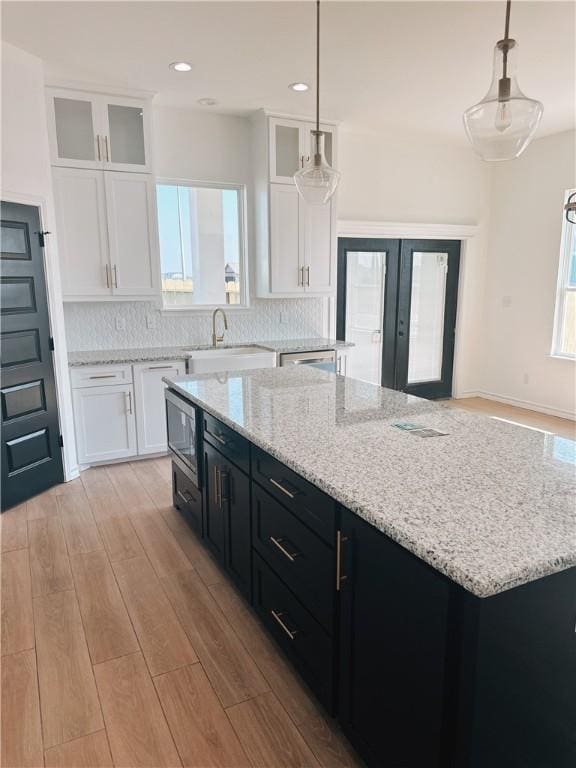 kitchen with white cabinets, dark cabinets, french doors, light wood-type flooring, and a sink