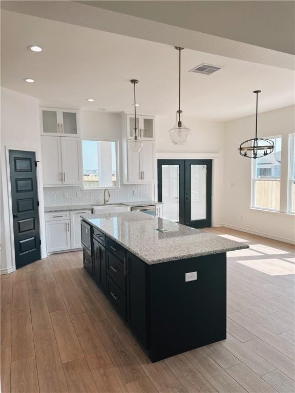 kitchen with light wood finished floors, visible vents, backsplash, and dark cabinets