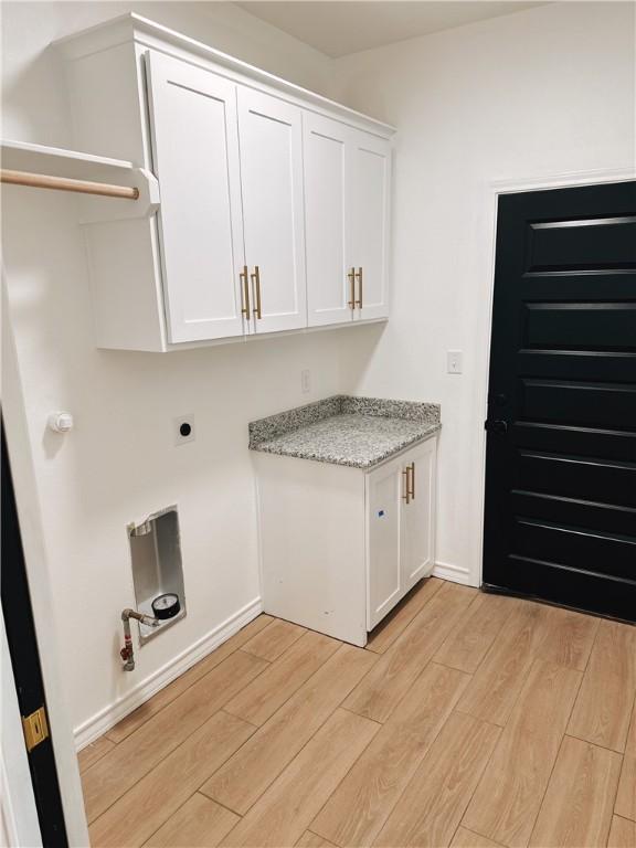 laundry area featuring baseboards, electric dryer hookup, cabinet space, and light wood-style floors