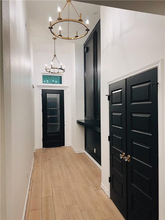 foyer entrance with a notable chandelier, baseboards, and light wood-style floors