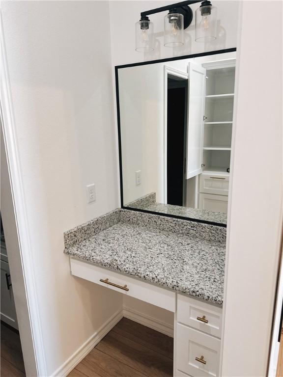 bathroom featuring baseboards, wood finished floors, and vanity