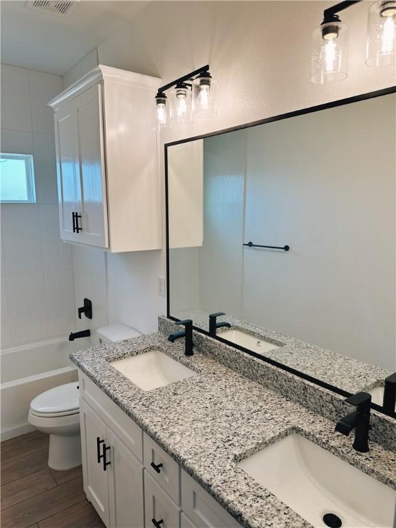 full bath featuring a sink, toilet, and wood finished floors