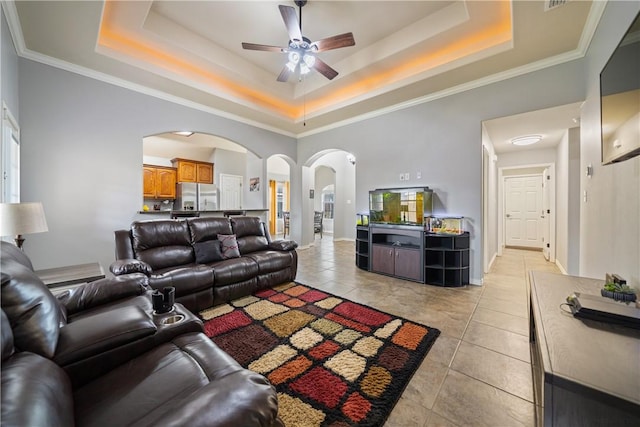 living room featuring ceiling fan, a raised ceiling, a high ceiling, and light tile patterned floors