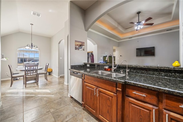 kitchen featuring sink, dark stone countertops, hanging light fixtures, stainless steel dishwasher, and a tray ceiling