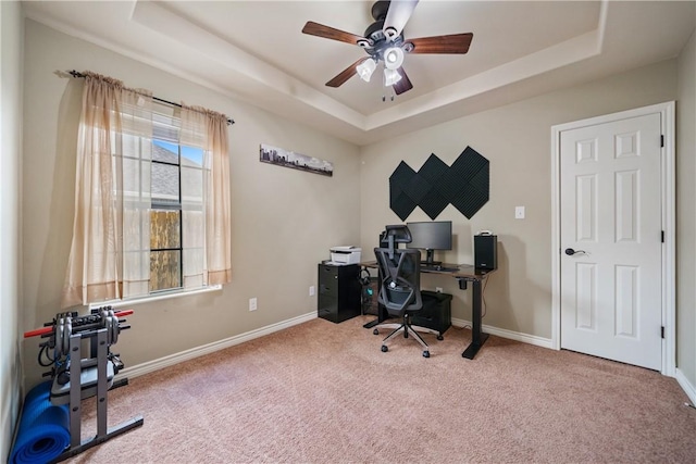 home office featuring carpet floors, ceiling fan, and a tray ceiling