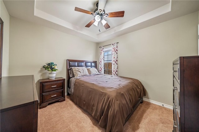 bedroom featuring ceiling fan, a raised ceiling, and light carpet