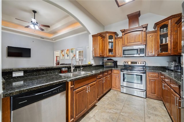 kitchen with a raised ceiling, sink, dark stone countertops, light tile patterned floors, and stainless steel appliances