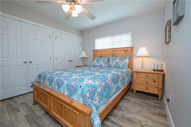 bedroom featuring ceiling fan, hardwood / wood-style flooring, and multiple closets