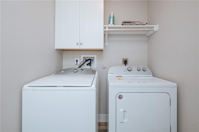 clothes washing area featuring cabinets and independent washer and dryer