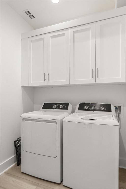 laundry room featuring cabinet space, baseboards, visible vents, light wood-style floors, and separate washer and dryer