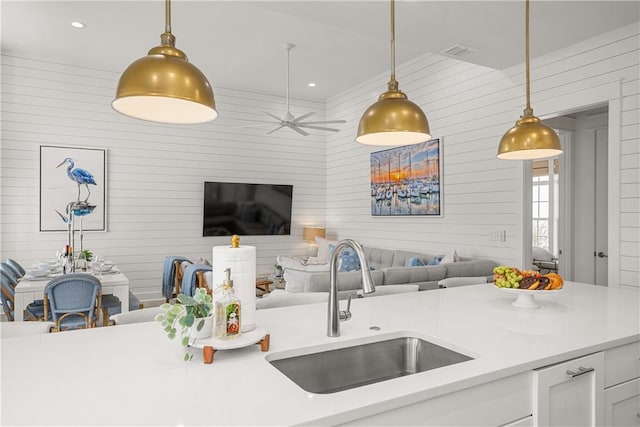 kitchen featuring open floor plan, light countertops, a sink, and pendant lighting