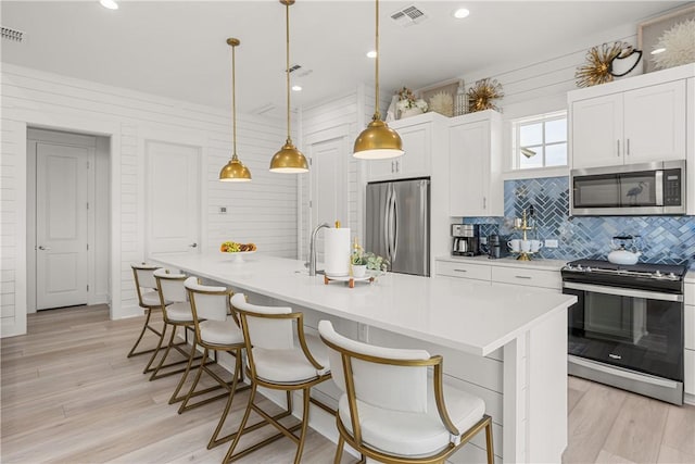 kitchen with stainless steel appliances, light wood finished floors, visible vents, and white cabinetry