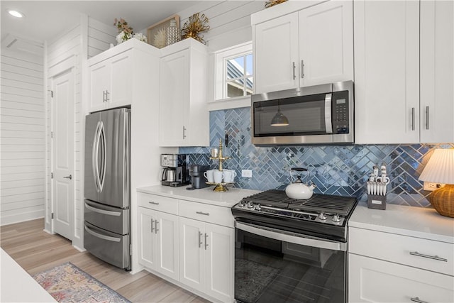 kitchen with white cabinets, light wood-style flooring, stainless steel appliances, and light countertops